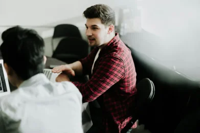 Mentor guiding a colleague during a professional coaching session with laptops.